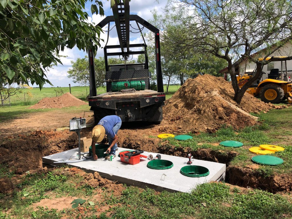 Technician installing a new septic tank in a residential yard